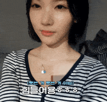 a woman wearing a striped shirt has a necklace with a heart pendant on it