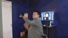 a man in a suit is dancing in a room in front of a computer screen .
