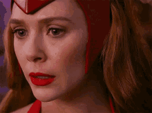a close up of a woman 's face with red lipstick and red eyes wearing a red helmet .