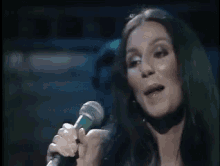 a woman is singing into a green microphone on a stage .