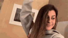a woman is taking a selfie with her hand in the air while wearing a hoodie .