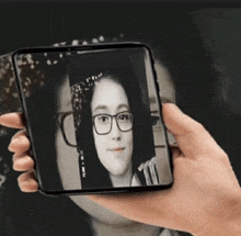 a person is holding a cell phone that has a picture of a girl with glasses on it