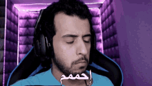 a man wearing headphones and a blue shirt with arabic writing