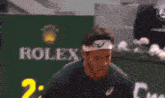 a man with a headband on his head is screaming while playing tennis .