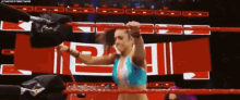 a woman is standing in a wrestling ring with her arms outstretched .