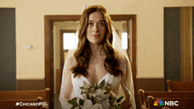 a woman in a wedding dress is holding a bouquet of flowers in a church