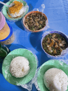 a blue table topped with bowls of food including rice and soup