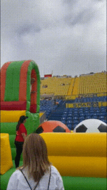 a woman stands in front of a bouncy house in a stadium that has the word calcio on it