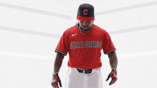 a baseball player wearing a red jersey that says guardians on the front