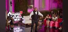 a man in a tuxedo is dancing in front of a group of people sitting on couch .
