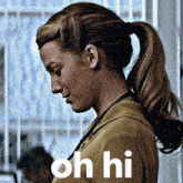 a woman in a ponytail is standing in front of a sign that says " oh hi "