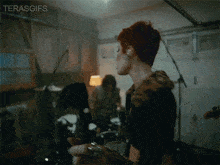 a woman with red hair is playing a guitar in a garage with the words terasgifs above her head