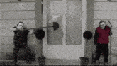 a man is holding a shovel over his head while another man stands next to him holding a hammer .