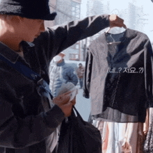 a man is holding a bag and looking at a clothes hanger with korean writing