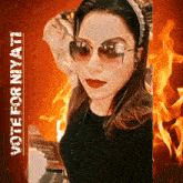 a woman wearing sunglasses stands in front of a fire with the words vote for niyan on the bottom
