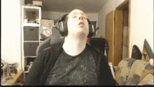 a man wearing headphones is sitting in a chair in a living room with his eyes closed .