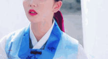 a close up of a woman wearing a blue and white kimono with a red ribbon around her head