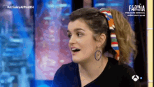 a woman wearing a ponytail and hoop earrings is on a television show