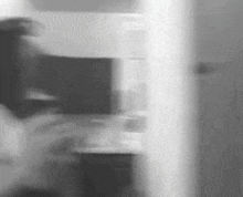 a black and white photo of a person standing next to a door .