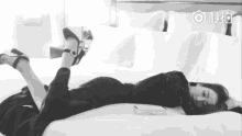 a black and white photo of a woman laying on a bed with her legs crossed