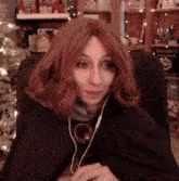 a woman with red hair is sitting in front of a christmas tree while wearing headphones .