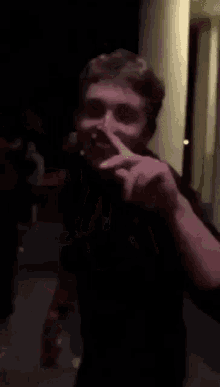 a man is making a peace sign with his finger while standing in a dark room .