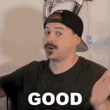 a man with a mustache wearing a hat and a black shirt with the word good on it
