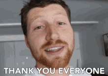 a man with a beard is smiling and says " thank you everyone "
