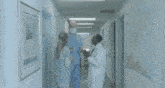 a group of people are running down a hallway in a hospital .