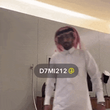 a man in a white shirt and a red head scarf is standing in front of a wall with the hashtag d7mi212