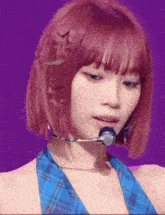 a woman with red hair is wearing a blue plaid top and a microphone