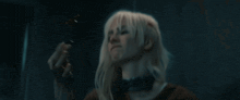 a woman with blonde hair is holding a knife in her hand .