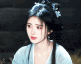 a woman wearing a blue dress and earrings is looking at the camera