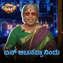 a man in a green and purple saree with a microphone on his neck and a sign that says ' '