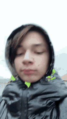 a boy wearing a black jacket with a hood