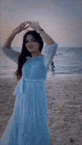 a woman in a blue dress is dancing on the beach