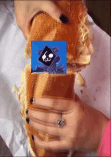 a person with a ring on their finger is holding a sandwich with a picture of a robot on it