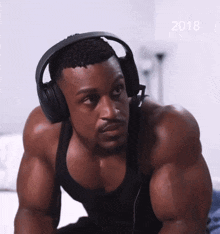 a muscular man wearing headphones with the year 2018 on the bottom right