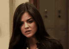 a woman with long dark hair is making a funny face while standing in front of a locker .