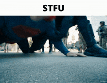 a man in a superman costume is crawling on the ground with the word stfu below him