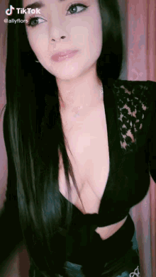 a woman with long black hair is wearing a very plunging neckline black top .