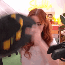 a woman with red hair is holding a black object in front of her face in a room .