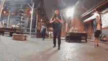a woman wearing a mask is dancing in front of a building