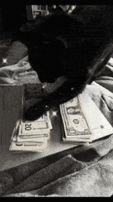 a black cat is playing with a stack of dollar bills