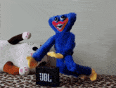 a jbl speaker sits next to a blue stuffed animal