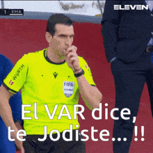 a referee with a yellow shirt that says fifa on the front