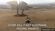 a man with a sword is standing in the desert next to a large robot .