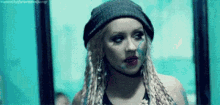 a woman with dreadlocks and a beanie is standing in front of a mirror .