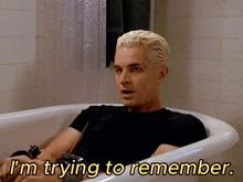 a man in a bathtub with the words " i 'm trying to remember " below him
