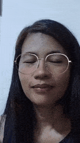 a woman with her eyes closed wearing round glasses